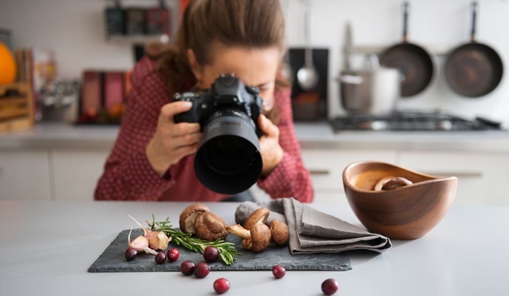 a girl taking pictures of garlic, mushroom and berries