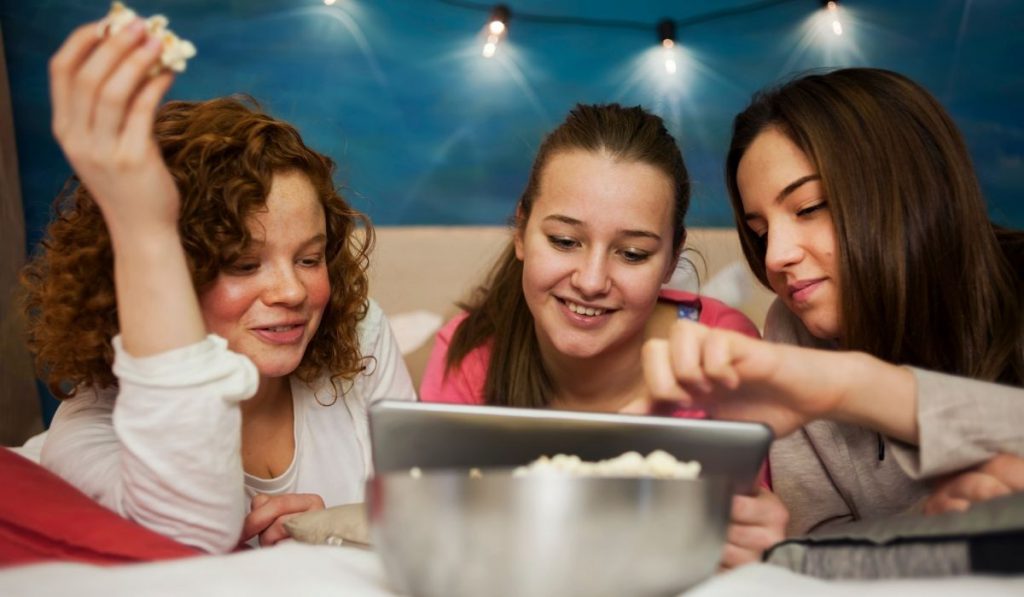 girls watching a movie with a popcorn at a pajama party